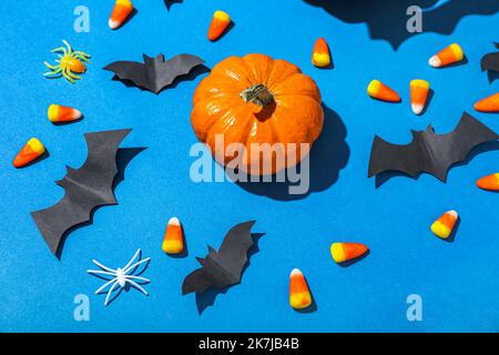 Papierfledermäuse mit Halloween Kürbis und Zuckerwangen auf blauem Hintergrund Stockfoto