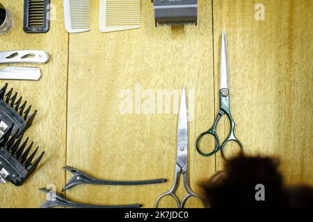 Draufsicht verschiedener professioneller Friseurwerkzeuge auf schwarzem Hintergrund. Stockfoto