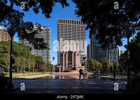 Ein Skater, der vor dem ANZAC Memorial und dem Reflecting Pool im Hyde Park in Sydney, Australien, einen Trick macht Stockfoto