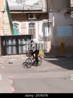 Ein älterer orthodoxer jüdischer Mann, der im Stadtteil Mea She'arim in Jerusalem, Israel, mit dem Fahrrad fährt. Stockfoto