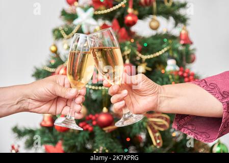 Unbekannte Erwachsene Paar Toasting während Weihnachten oder Neujahr, feiern Feiertage zusammen. Nahaufnahme einer weiblichen und männlichen Hand, die ein Paar anklirren Stockfoto