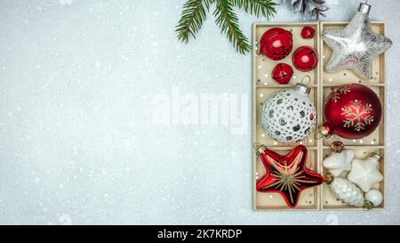 weihnachtsschmuck in Holzkiste. Rote und silberne weihnachtssterne, Glaskugeln und Glocken. Stockfoto