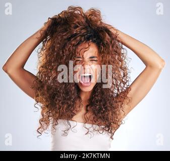 Es ist ein Alptraum. Eine attraktive junge Frau, die vor grauem Hintergrund frustriert im Studio aussieht. Stockfoto