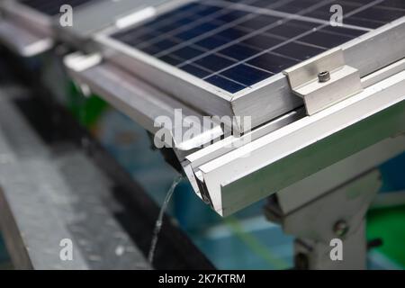 Nahaufnahme der Installation von Photovoltaikanlagen mit Regenrinne. Solarzellenpanel. Stockfoto
