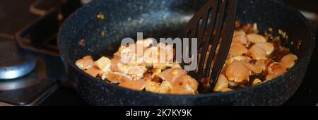 Schweinefleisch oder Hühnchen mit Zwiebeln werden in einer Pfanne gebraten Stockfoto