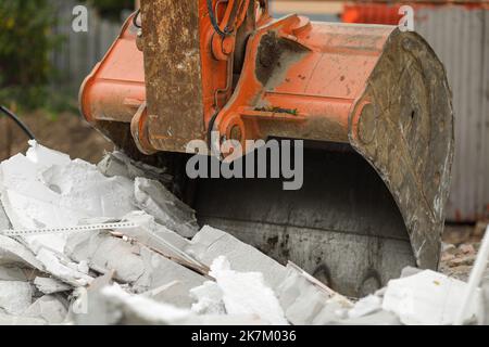 Details mit einem Baggereimer (Schaufel), der zum Abriss eines kleinen AAC-Gebäudes verwendet wurde. Stockfoto