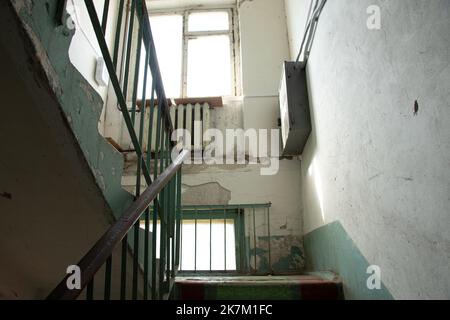 Alte schmutzige Treppe ohne Reparatur mit einer Treppe in einem Wohnhaus in der Ukraine, einem Eingang in einem mehrstöckigen Gebäude Stockfoto