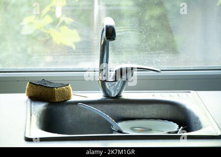 Schmutziges Geschirr im Waschbecken auf dem Tisch in der Küche unter fließendem Wasser, schmutziges Geschirr im Mokka in der Küche zu Hause Stockfoto