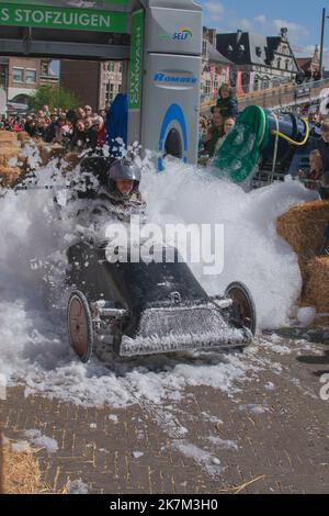 Sint Niklaas, Belgien, 05. Mai 2019, der Mann mit schwarzem Helm fährt während eines Seifenkastenrennens einen maßgefertigten Go-Kart durch einen Berg aus Schaum Stockfoto