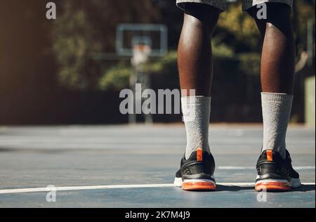 Basketball, Sneaker und der schwarze Sportler, der auf dem Community-Sportplatz für Spiel, Motivation und Streetball-Erinnerung steht. Männlicher Spieler außerhalb der USA Stockfoto