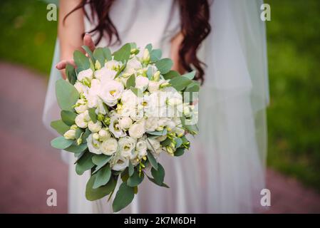 Die Braut hält einen Brautstrauß aus Rosen in den Händen, Hochzeitstag Blumen. Schöner Bohemian Hochzeit Blumenstrauß. Mädchen in einem Kleid mit einem Bouq Stockfoto