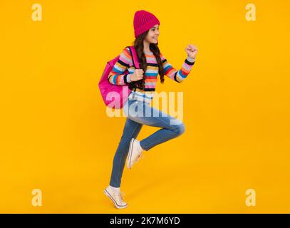 Schulferien im Herbst. Zurück zur Schule. Teenager Schülerin im Herbst Kleidung auf gelb isoliert Studio Hintergrund. Springen und laufen, springen Kinder. Stockfoto