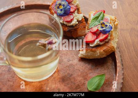 Strawberry Toast Brioche mit Frischkäse mit Blumen verziert und Basilikum flach legen aus der Nähe Stockfoto