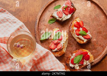 Strawberry Toast Brioche mit Frischkäse mit Blumen verziert und Basilikum flach legen aus der Nähe Stockfoto