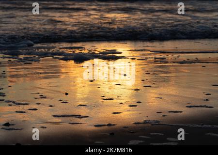 Schöner Sonnenuntergang am Sandstrand der Ostsee mit Wellen und Reflexionen auf dem Wasser Stockfoto