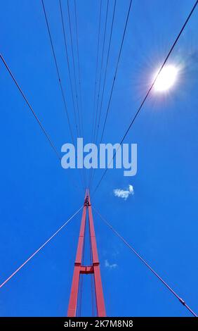 Von der modernen Hängebrücke mit Sonne und blauem Himmel nach oben geschossen. Stockfoto