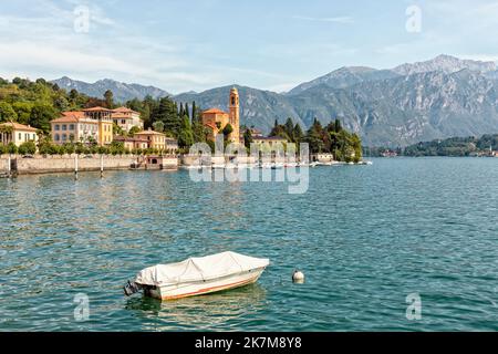 Tremezzo am westlichen See des Comer Sees, Lombardei, Italien mit Kirche von San Lorenzo und Yachthafen. Festfahrtes Boot im Vordergrund. Stockfoto