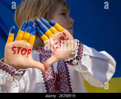 Junge in nationalen ukrainischen Kleidern legte seine gelb-blauen Hände vor, mit der Aufschrift STOP war auf ihnen. Russlands Invasion der Ukraine, Kinder Stockfoto