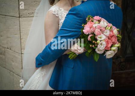 Die Braut hält einen Brautstrauß aus Rosen in den Händen, Hochzeitstag Blumen. Schöner Bohemian Hochzeit Blumenstrauß. Mädchen in einem Kleid mit einem Bouq Stockfoto