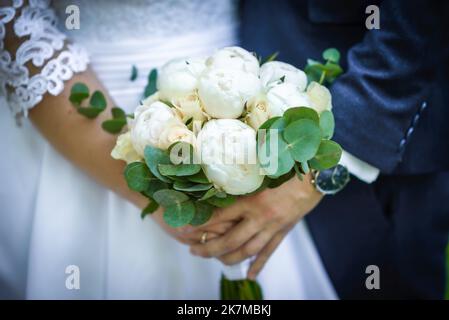 Die Braut hält einen Brautstrauß aus Rosen in den Händen, Hochzeitstag Blumen. Schöner Bohemian Hochzeit Blumenstrauß. Mädchen in einem Kleid mit einem Bouq Stockfoto