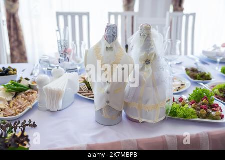 Flasche Champagner im Eimer mit Eis und Gläsern auf verschwommenem Hintergrund, Nahaufnahme. Flaschen Champagner bei der Hochzeit auf dem Tisch Stockfoto