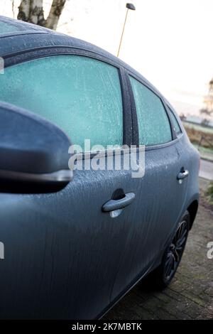 Ein Porträt eines gefrorenen Seitenspiegels und Seitenscheiben eines komplett gefrorenen Autos im Winter. Das Eis muss zuerst schmelzen oder bef entfernt werden Stockfoto