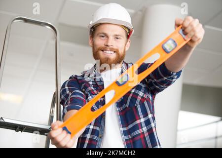 Blasenhöhe durch lächelnden Baumeister gehalten Stockfoto