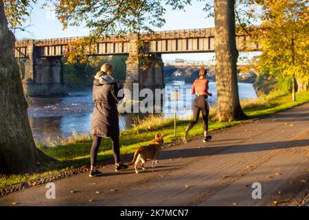 Preston, Lancashire. Wetter in Großbritannien; 18. Oktober 2022. Die Sonne geht über dem River Ribble auf, während die Anwohner in der Morgendämmerung am Riverside Walk, einem kalten nebligen Start in den Tag, leichte Übungen machen. Avenham Park Familienbereich, Rad- und Wanderwege im Nordwesten Englands. Kredit; MediaWorldImages/AlamyLiveNews Stockfoto