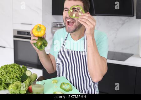 Mann spielt mit grünen Paprika in der Küche Stockfoto