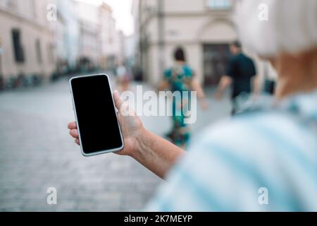 Nahaufnahme von weiblichen Händen mit Smartphone auf der Einkaufsstraße der Stadt, Suche oder Social-Networks-Konzept Stockfoto