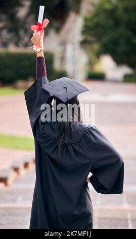 Bildung kann die Welt verändern. Rückansicht einer nicht erkennbaren jungen Studentin, die am Abschlusstag feiert. Stockfoto