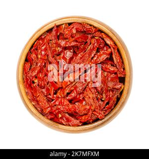 Sonnengetrocknete Tomaten, in einer Holzschüssel, von oben isoliert. Rote reife Tomaten, in Julienne-Streifen geschnitten, gesalzen und dann in der Sonne getrocknet. Stockfoto