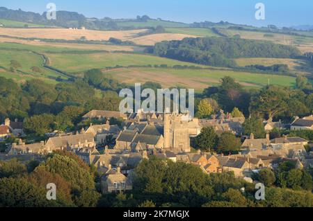 Malerische Aussicht auf den St. Edwards Church Tower, die Pfarrkirche im Dorf Corfe Castle, mit Häusern im Spätsommer auf dem Land, Dorset, England, Großbritannien Stockfoto