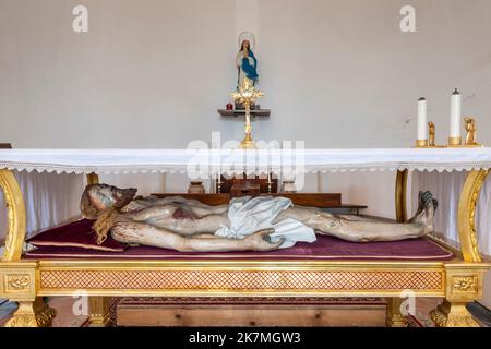 Eine brutal realistische, lebensgroße Statue der Leiche Jesu nach seiner Kreuzigung in einer kleinen sizilianischen Dorfkirche (Italien) Stockfoto