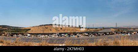 Ein Panoramablick auf die sizilianische Landschaft mit Müll, der am Straßenrand gedumpt wird, ein häufiger Anblick über Sizilien in ländlichen Gebieten und Städten Stockfoto