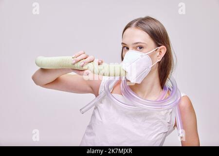 Close-up-Porträt von jungen schönen Mädchen, die tief Atem in spezielle Maske isoliert über grauen Hintergrund Stockfoto