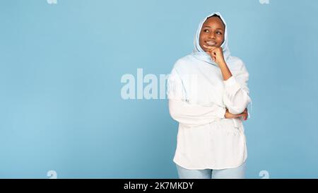 Porträt einer nachdenklichen afroamerikanischen muslimischen Frau mit leichtem Kopftuch, die das Kinn berührt und in den freien Raum blickt Stockfoto