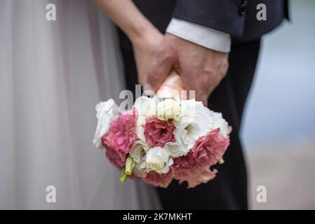 Die Braut hält einen Brautstrauß aus Rosen in den Händen, Hochzeitstag Blumen. Schöner Bohemian Hochzeit Blumenstrauß. Mädchen in einem Kleid mit einem Bouq Stockfoto