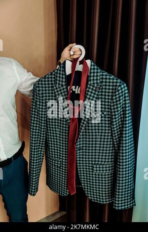Stilvoller, eleganter Hochzeitsanzug mit Aufhängung im Hotelapartment. Hochzeitszubehör für den Bräutigam. Stockfoto