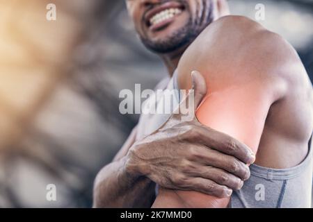 Ich habe mich zu sehr belastet. Nahaufnahme eines nicht erkennbaren Mannes, der seinen Arm vor Schmerzen hielt, während er in einem Fitnessstudio trainierte. Stockfoto