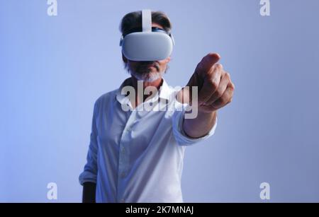 Geschäftsmann, der mit virtuellem Raum interagiert, während er eine Virtual-Reality-Schutzbrille trägt. Ein Geschäftsmann, der mit dem Finger einen virtuellen Knopf drückt. Matur Stockfoto