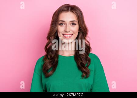 Foto von guter Laune optimistische Frau mit lockigen Frisur gekleidet grün T-Shirt lächelt an der Kamera isoliert auf rosa Hintergrund Stockfoto