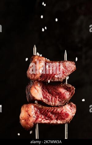 Eine Nahaufnahme von Steakstücken auf zwei Metallspießen Stockfoto