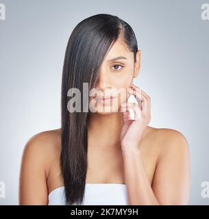 Gerade Haare geben mir so viel Selbstvertrauen. Eine junge Frau, die allein steht und posiert, wobei ihr Haar die Hälfte ihres Gesichts im Studio bedeckt. Stockfoto