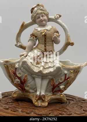 Eine Vintage-Porzellanfigur des Mädchens durch den Brunnen, vertikale Aufnahme Stockfoto