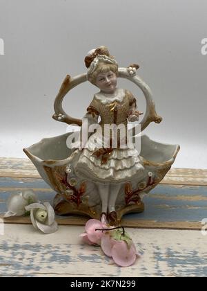 Eine Vintage-Porzellanfigur des Mädchens durch den Brunnen, vertikale Aufnahme Stockfoto