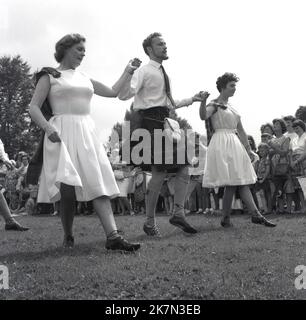 1964, historisch, ein Mann mit zwei Damen auf einem Feld schottischer Tanz, der Mann mit einem Kilt, auf einem Dorffest, Weston Terville, Buckinghamshire, England, Großbritannien. Vielleicht Aylesbury? Stockfoto