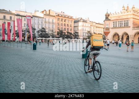 Krakau, Polen - 25. August 2022: Ein nicht identifizierter Glovo-Fahrradkurier auf der Straße in Krakau, Polen. Lieferung von Lebensmitteln, Produkten Stockfoto