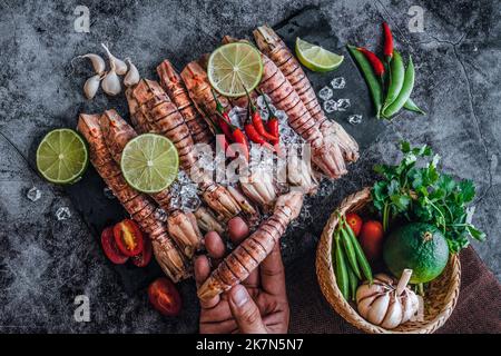 Ein Blick von oben auf rohe Mantis Garnelen, Limettenscheiben, Knoblauch und Paprika auf einem Tisch Stockfoto