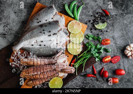 Ein Blick von oben auf rohen frischen Fisch und Krabben, Limetten, Knoblauch, Paprika und Salz auf einem Tisch Stockfoto